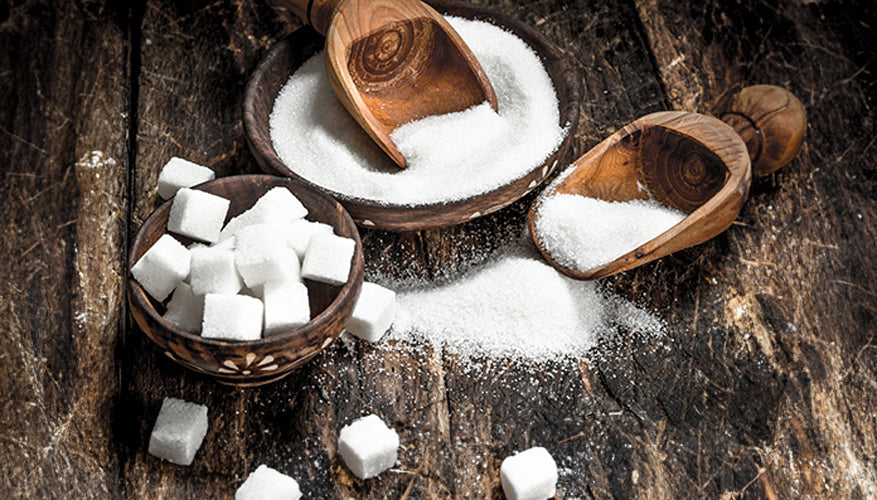 refined sugar pile with scoops, and sugar cubes on wood surface