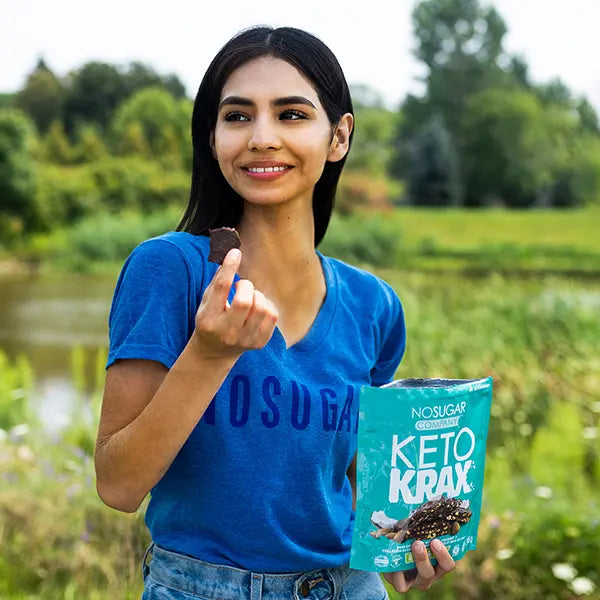 Girl eating No Sugar Company chocolate Keto Krax in field